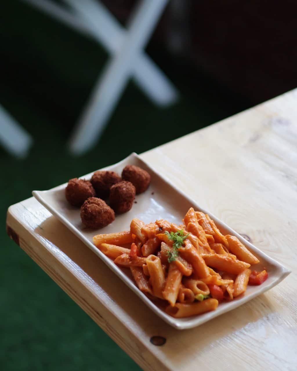 Red sauce penne with paneer bites on a cream handmade tray