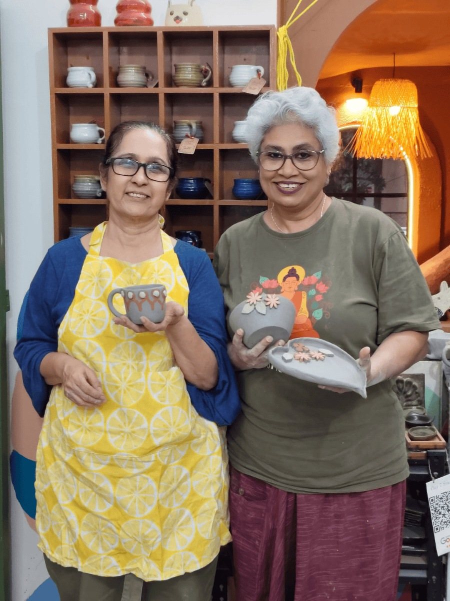 Two women showing off their painted pieces