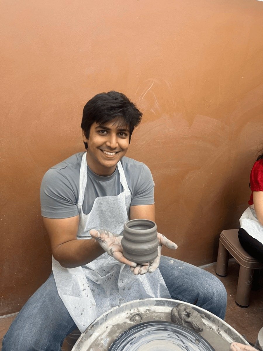 A guest throwing a pot on the wheel against the studio's terracotta wall